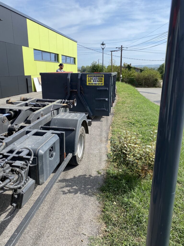 Camion ampliroll qui dépose une benne Guerdner le long du bâtiment du client