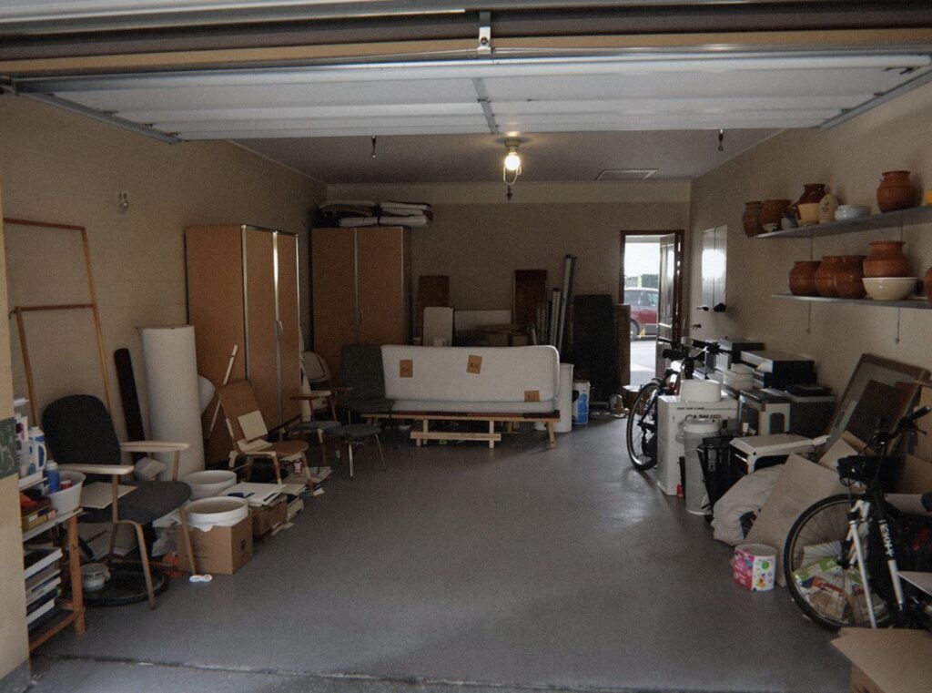 Garage de Villeurbanne rempli de vieux meubles, de cartons et de matelas avant la benne