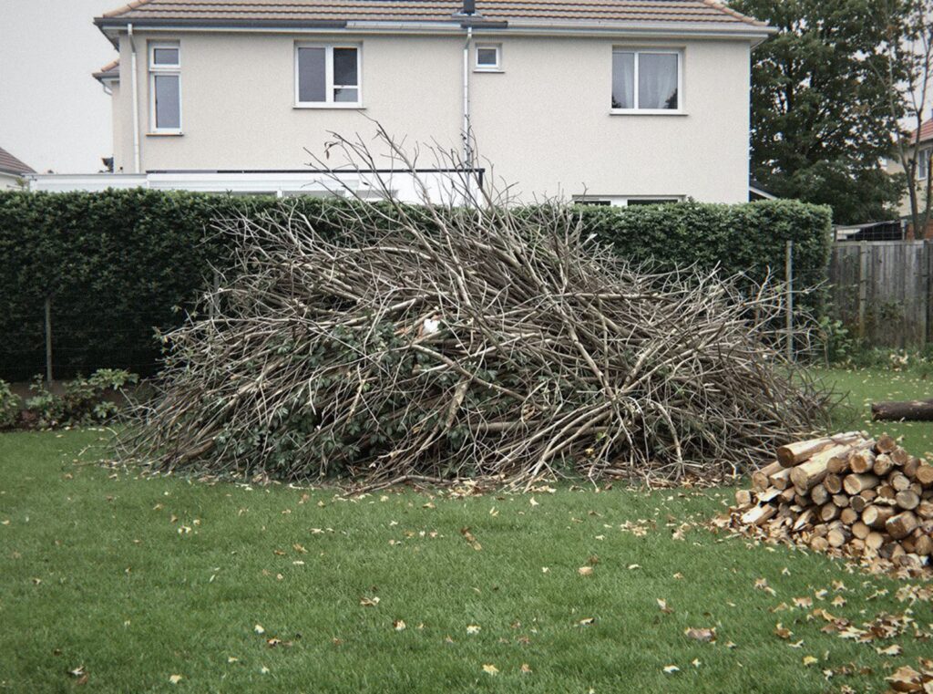 Grand tas de branches et de haie taillée sur la pelouse d'un jardin à Bron